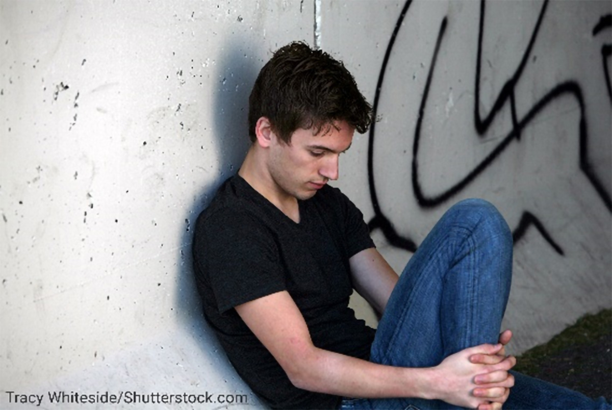 photo of youth sitting on ground, in deep thought