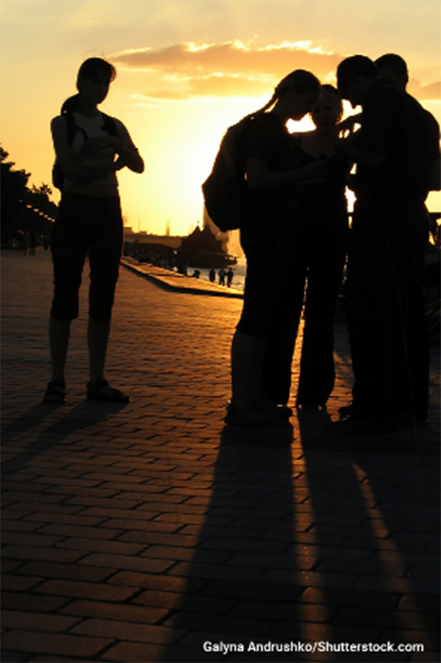 Stock photo of the silhouettes of a group of youth during sunset