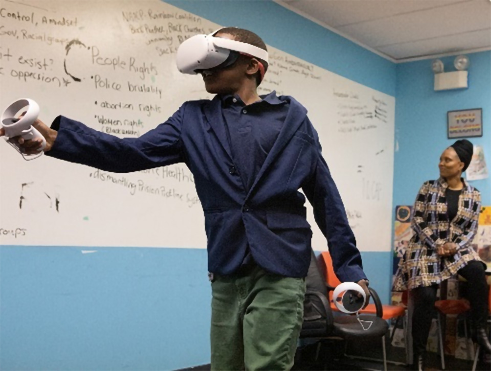 Photo of a youth demonstrating the use of a virtual reality headset and controllers during an October 2022 media event