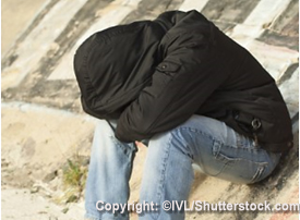 Depressed teen boy with head in arms.