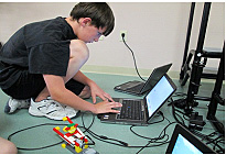 Carter Smith, 11, programs a computer to bring a robot he built to life. 