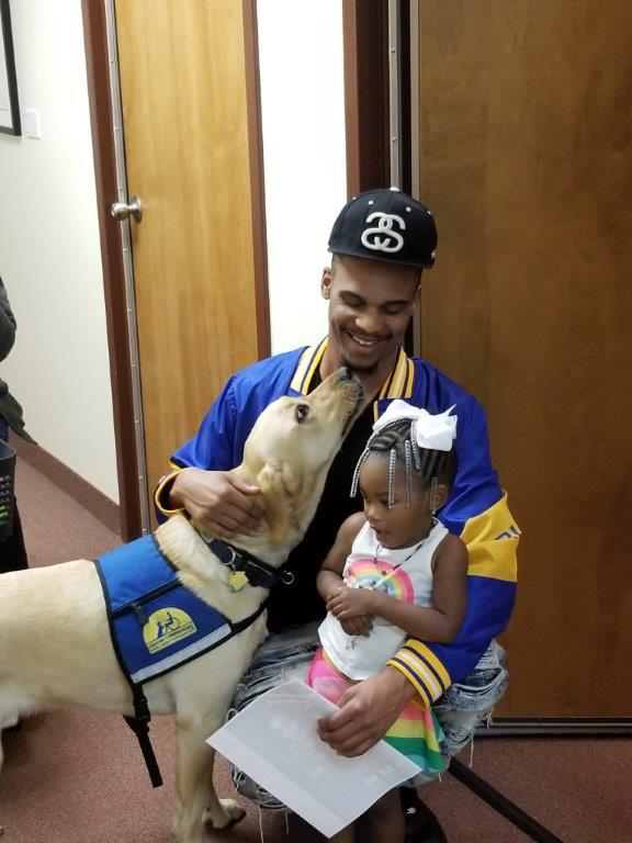 Photo of Darius, a Strengthening Fathers program participant, with his daughter and The Up Center's service dog.