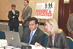 Attorney General Alberto Gonzales, with Michelle Collins of the National Center for Missing and Exploited Children, views a demonstration of the Child Victim Identification Lab.