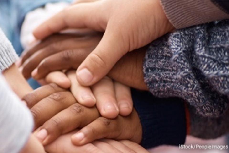 Stock photo of several children stacking their hands together