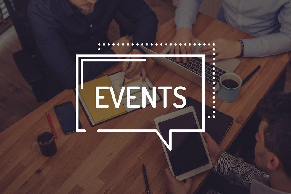 Events written on top of a group of people sitting around a table on electronic devices
