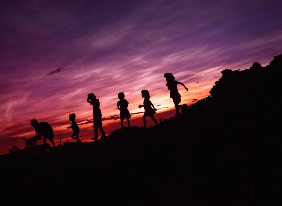 Kids playing with their dog during sunset.
