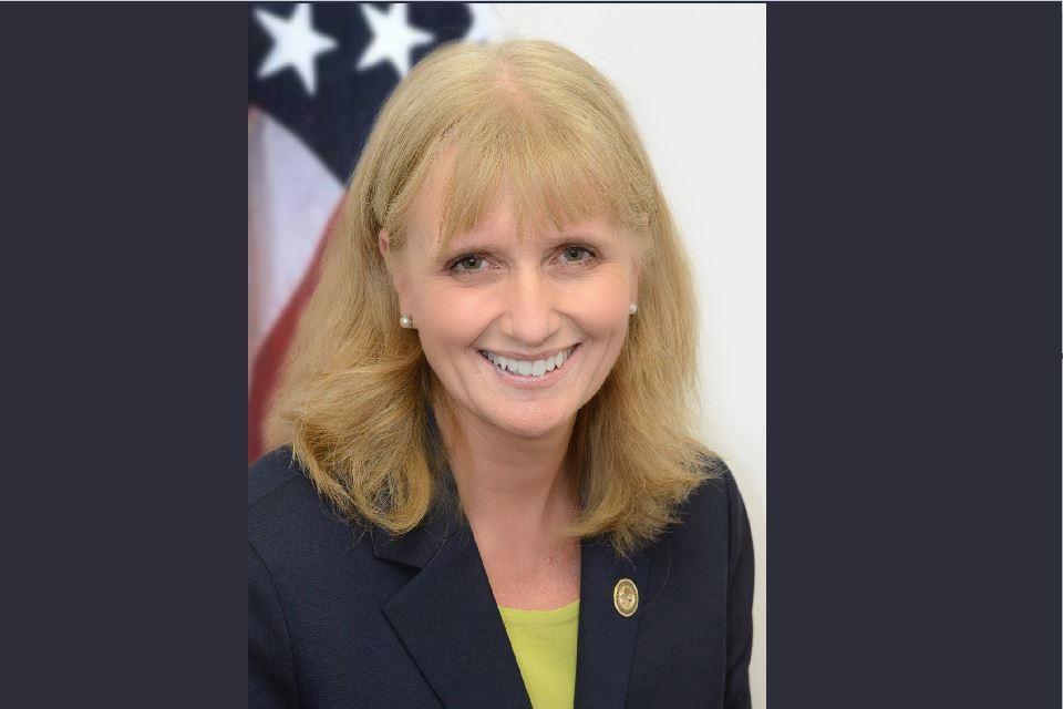 OJJDP Administrator Caren Harp pictured in front of an American Flag